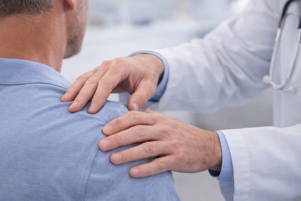 Close up of a doctor's hands gently examining a patient's shoulder joint